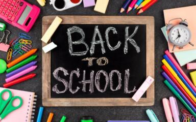 A blackboard with 'Back to School' written on it in chalk, surrounded by school supplies.